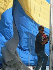 Das Streif-/Gegenlicht lässt den Spinnaker leuchten, durch die lange Brennweite wurde der Vorschiffmann eingefangen, wie er versucht, das Segel zu bändigen [Foto: MediaNord]