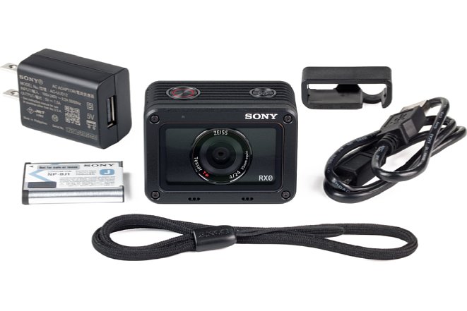 Bild Lieferumfang der Sony DSC-RX0: Kamera, Akku, Handschlaufe (vorne), USB-Kabel, Ladegerät und Kabelführung. [Foto: MediaNord]