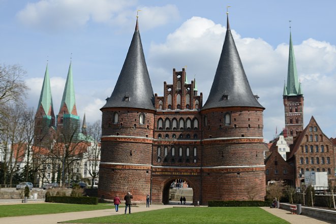 Bild Auch wenn das Lübecker Holstentor durch seine baulich beeinträchtigte Symmetrie immer asymetrisch aussieht, kann man stürzende Linien an der Petrikirche (rechts) und der Marienkirche (links) sowie dem Salzspeicher (rechts vorne) erkennen. [Foto: MediaNord]