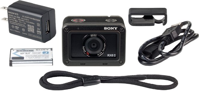 Bild Lieferumfang der Sony DSC-RX0 II: Kamera, Akku, Handschlaufe (vorne), USB-Kabel, Ladegerät und Kabelführung. [Foto: MediaNord]